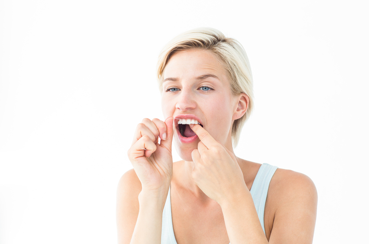 Blonde woman flossing on white background