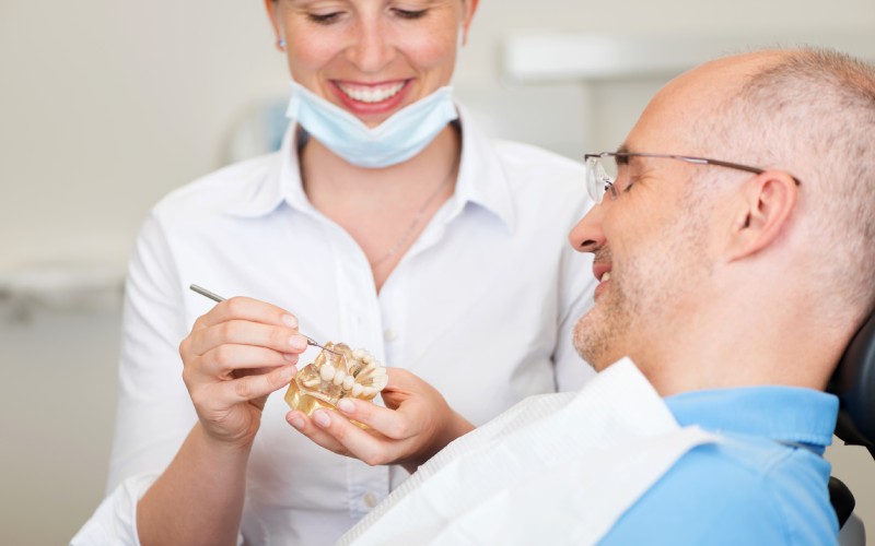 smiling female dentist explaining artificial teeth